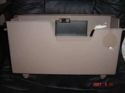 1993 Ford Bronco - This is a tan glove box door with a black latch, shown resting on a black leather seat.
