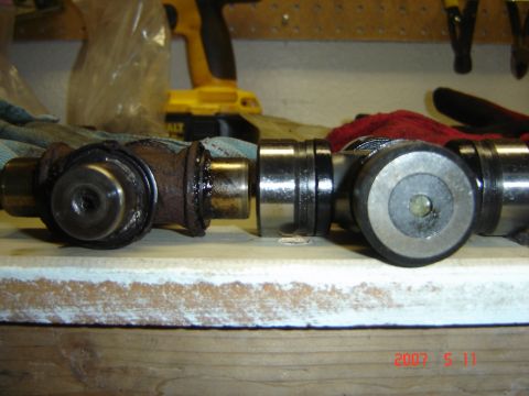 1993 Ford Bronco - Comparison of a worn driveshaft U-joint with a new one, highlighting the difference in condition.