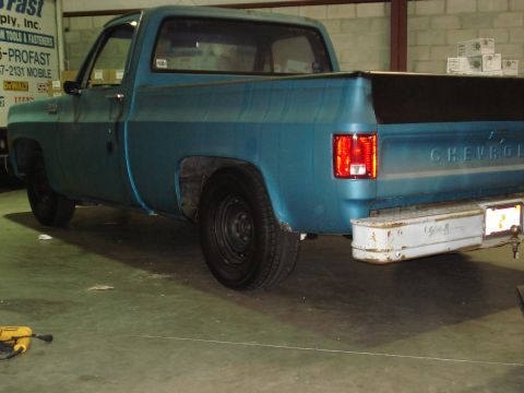 1979 Chevrolet C/K Pickup - The rear of a blue pickup truck is shown, with the CHEVROLET name visible on the tailgate.