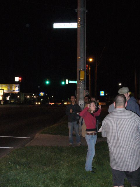 1991 Ford Probe - A group of people are gathered at an intersection at night, with traffic lights and street signs visible.