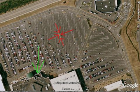 1986 Ford Bronco - An aerial view shows a vast parking lot filled with numerous vehicles, with red arrows highlighting a specific section.