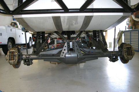 1996 Ford Bronco - Underside rear view of a vehicle showing a custom fabricated rear axle with a large center differential housing, coilover shocks, multiple…