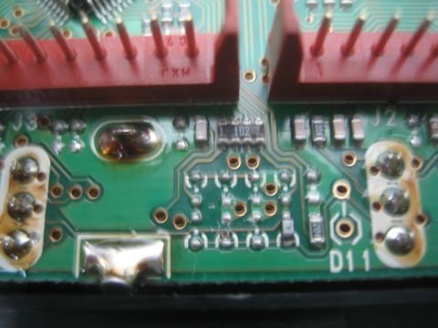 1990 Ford Bronco - Macro of a green printed circuit board showing red connectors and silkscreen markings J3, J2 and D11.