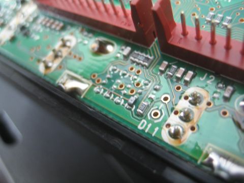 1990 Ford Bronco - Angled close-up of a green printed circuit board with a red connector header and silkscreen labels J2 and D11.