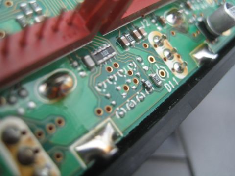 1990 Ford Bronco - Tight macro of a green printed circuit board edge with red connectors, solder joints and labels J2 and D11.