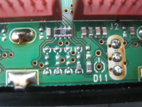 1990 Ford Bronco - Close-up of a green printed circuit board with red headers, surface-mount components and silkscreen labels J2 and D11.