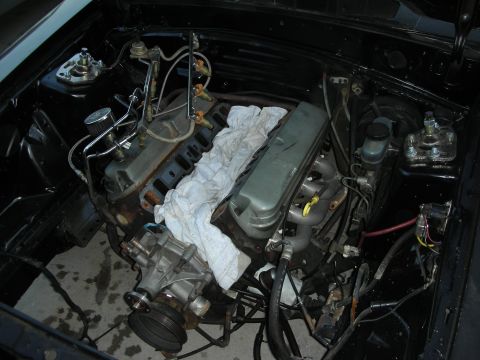 1998 Ford Crown Victoria - engine bay with a rag draped over the valve cover, showing exposed manifolds and wiring during service work.