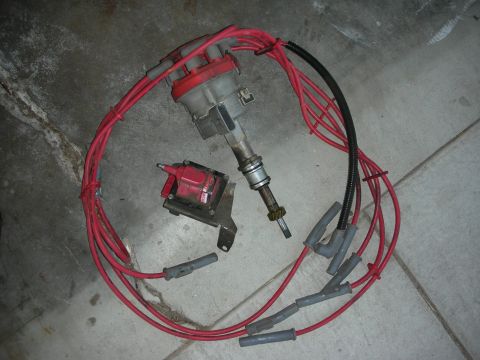 1998 Ford Crown Victoria - A set of red spark plug wires and a distributor are laid out on a concrete surface.