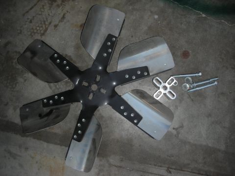 1998 Ford Crown Victoria - A six-blade cooling fan and its mounting hardware are laid out on a concrete floor.