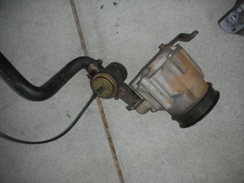 1998 Ford Crown Victoria - A close-up view of a vacuum hose and valve assembly, likely a car part, resting on a concrete surface.