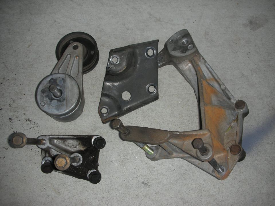 Engine belt tensioner assembly, a metal bracket, and a smaller bracket with bolts