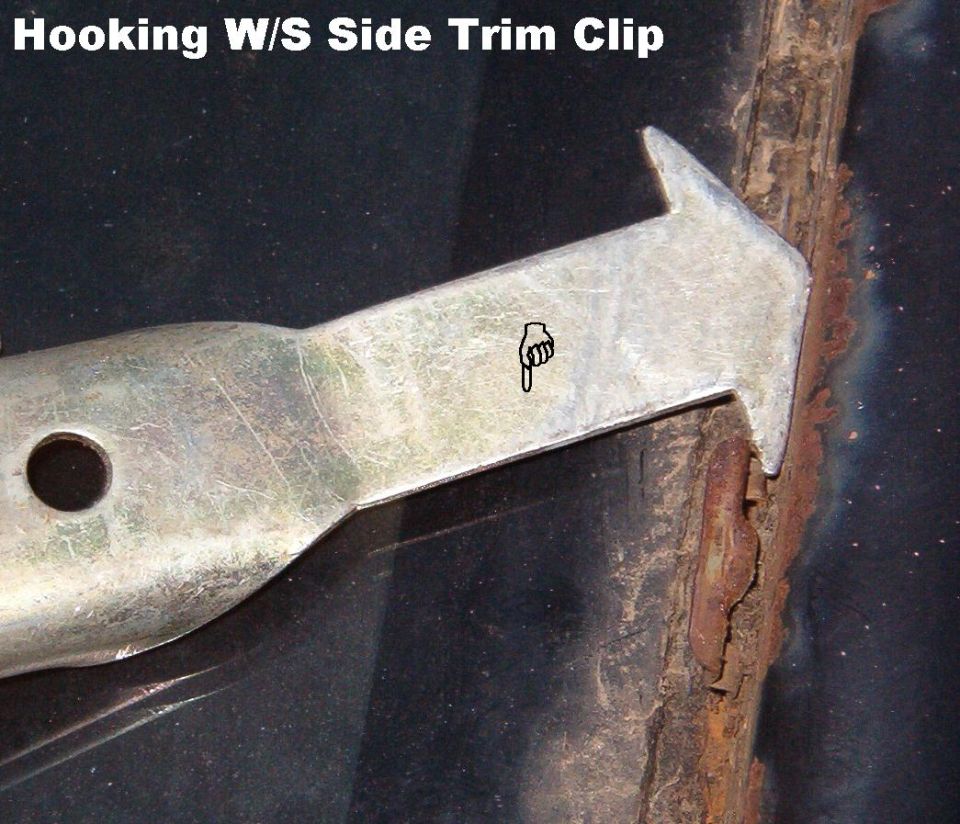Close-up of metal trim tool hooking a windshield side trim clip