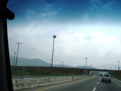 1995 Ford F-150 - View from a vehicle traveling on a highway with a concrete barrier and distant mountains.
