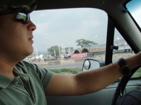 1995 Ford F-150 - A driver's perspective from inside a vehicle, looking out at a landscape with tents and advertisements.