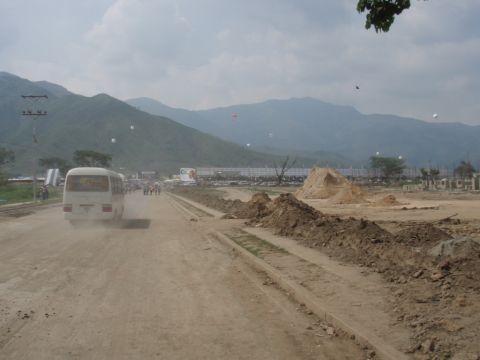 1995 Ford F-150 - A white van kicks up dust as it drives down a dirt road, with mountains visible in the distance.