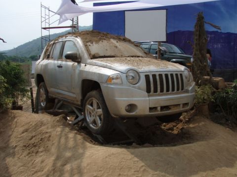 1995 Ford F-150 - A silver Jeep Compass is shown on a dirt obstacle course, with mud covering its hood and roof.