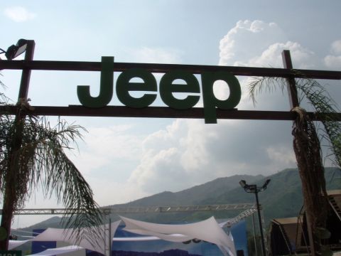 1995 Ford F-150 - A large Jeep sign is visible against a cloudy sky, with mountains and palm trees in the distance.