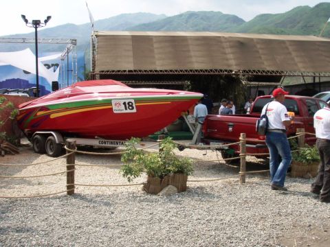 1995 Ford F-150 - A red boat with racing number 18 is parked on a trailer next to a red pickup truck at an outdoor event.