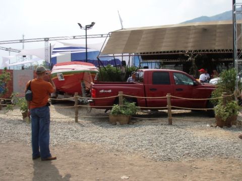 1995 Ford F-150 - A red pickup truck tows a boat on a trailer near a covered structure.