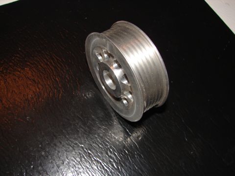 1992 Ford Taurus - A metal pulley with multiple grooves sits on a textured black surface.