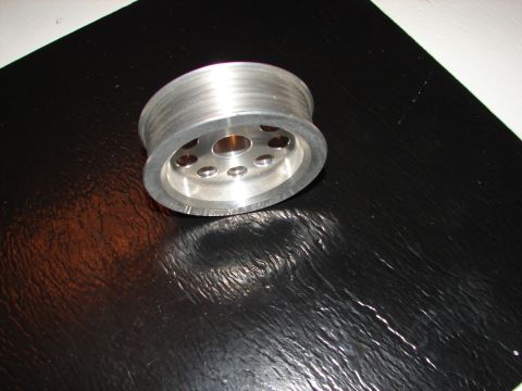 1992 Ford Taurus - An aluminum pulley, likely a car part, is shown on a black textured surface.