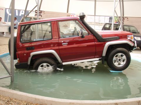 1995 Ford F-150 - Red Toyota Land Cruiser 70 Series with snorkel is shown driving through a water feature.