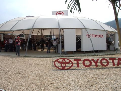1995 Ford F-150 - A Toyota branded tent is set up outdoors, with people milling around inside and a large TOYOTA sign displayed prominently.