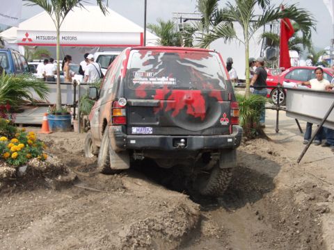 1995 Ford F-150 - A Mitsubishi Pajero navigates a challenging off-road course, with a Mitsubishi Motors tent visible in the background.