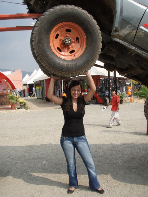 1995 Ford F-150 - A woman poses with a tire from a vehicle lifted off the ground.