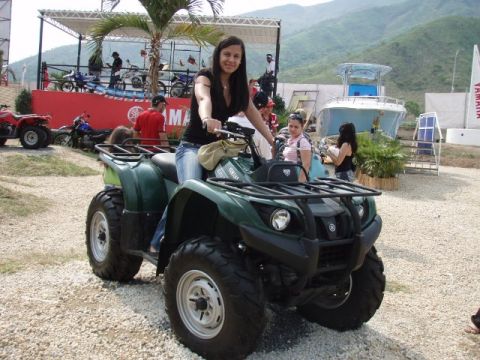1995 Ford F-150 - A woman poses on a green ATV at an outdoor event with other vehicles and a boat visible.