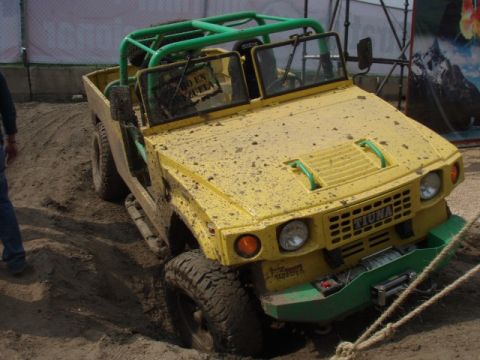 1995 Ford F-150 - This yellow off-road vehicle with a green roll cage is stuck in the dirt.