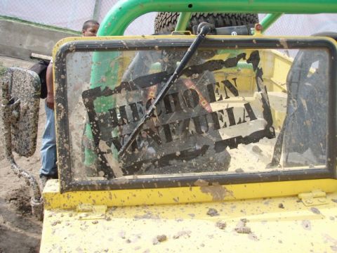1995 Ford F-150 - The rear window of a yellow off-road vehicle is covered in mud and features a 'Hecho en Venezuela' sticker.
