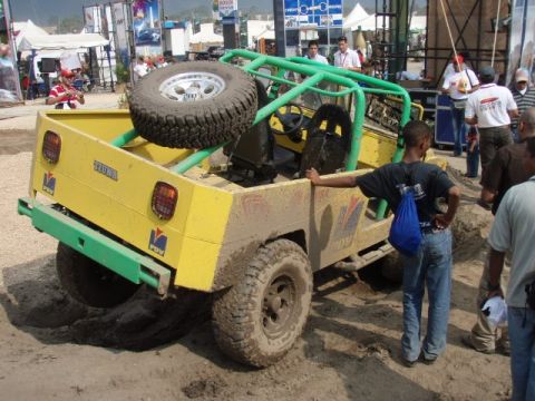 1995 Ford F-150 - A yellow off-road vehicle is stuck in the mud, with a spare tire visible in the cargo area.