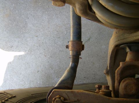 2004 Jeep Wrangler - This image shows a close-up view of a vehicle's suspension system, focusing on rusty metal parts and a tire.
