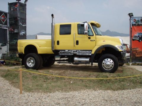 1995 Ford F-150 - A yellow crew cab truck with a prominent exhaust stack is parked outdoors.