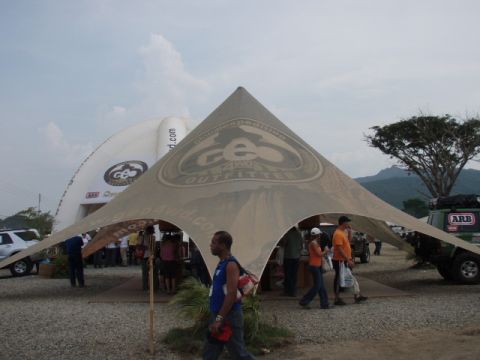 1995 Ford F-150 - An outdoor event features a green SUV with ARB branding parked under a large tent with people milling around.