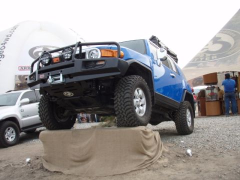 1995 Ford F-150 - A blue Toyota FJ Cruiser is shown with off-road modifications, positioned on a display ramp.