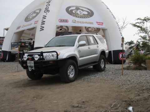 1995 Ford F-150 - Silver SUV with off-road modifications is parked in front of a large inflatable structure with various logos.