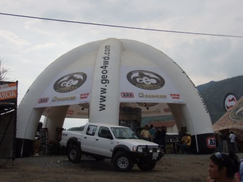 1995 Ford F-150 - A white pickup truck is displayed under a large inflatable archway with sponsor logos and website addresses.