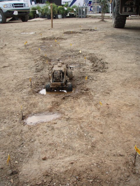 1995 Ford F-150 - A remote-controlled toy bulldozer navigates a muddy obstacle course with flags marking the path.