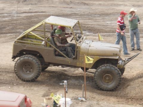 1995 Ford F-150 - Off-road vehicle with custom roll cage and large tires navigates a dirt course.