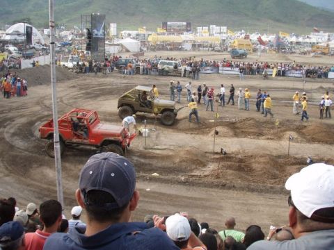 1995 Ford F-150 - A crowd watches as modified off-road vehicles navigate a challenging dirt course during an event.