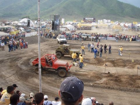 1995 Ford F-150 - A crowd watches as a red off-road jeep navigates a challenging course at an outdoor event.