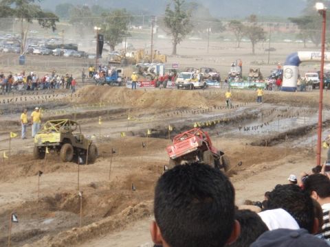 1995 Ford F-150 - Multiple off-road vehicles compete on a challenging muddy track during an event.