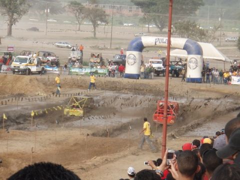 1995 Ford F-150 - Vehicles compete in a mud race event, with spectators watching from the side.