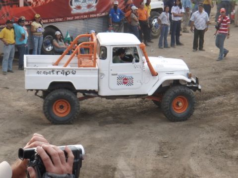 1995 Ford F-150 - A modified white pickup truck with an orange roll cage and snorkel is seen from the side.