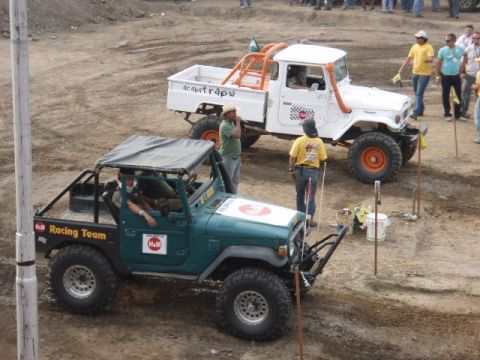 1995 Ford F-150 - Two modified off-road vehicles are parked on a dirt track, possibly before or after an event.