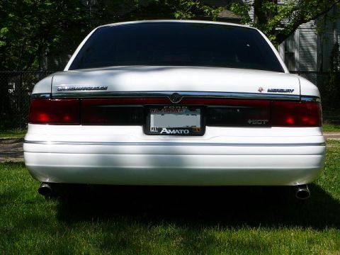 1997 Mercury Grand Marquis - The rear of a white Mercury Grand Marquis is shown parked on grass with trees in the background.