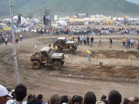 1995 Ford F-150 - Off-road vehicles compete in a dirt arena with a crowd watching.