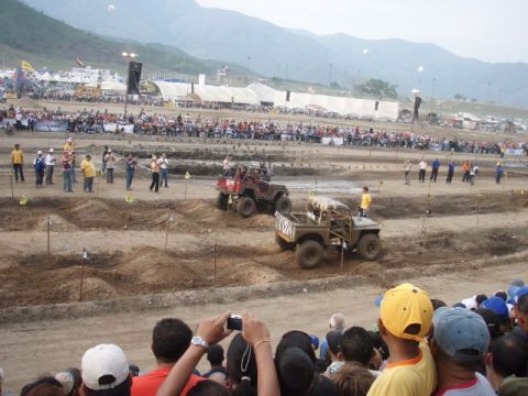 1995 Ford F-150 - Spectators watch as two off-road vehicles navigate a challenging dirt course during a competition.